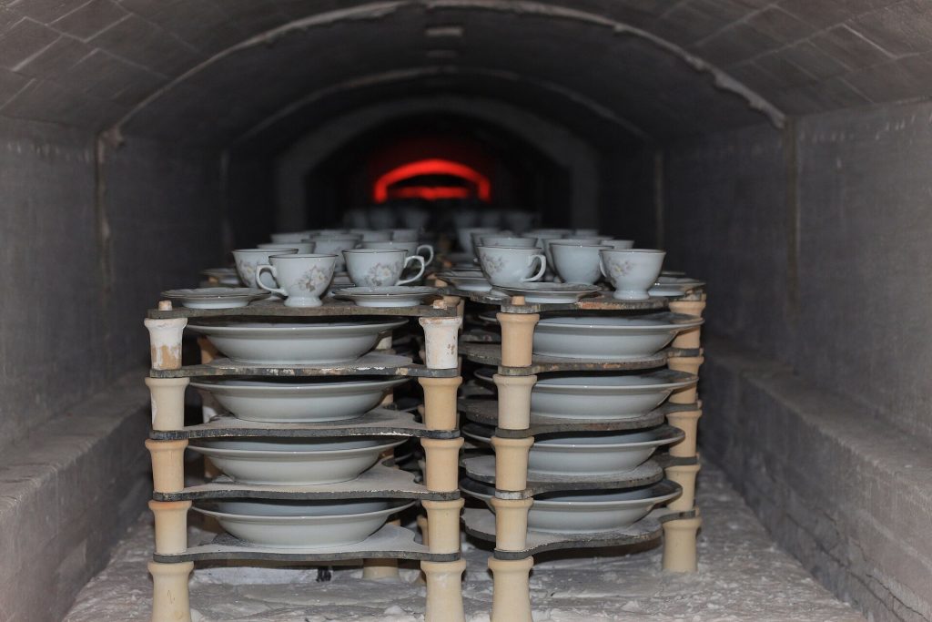 Porcelain stacked inside a kiln with fire glowing at the far end